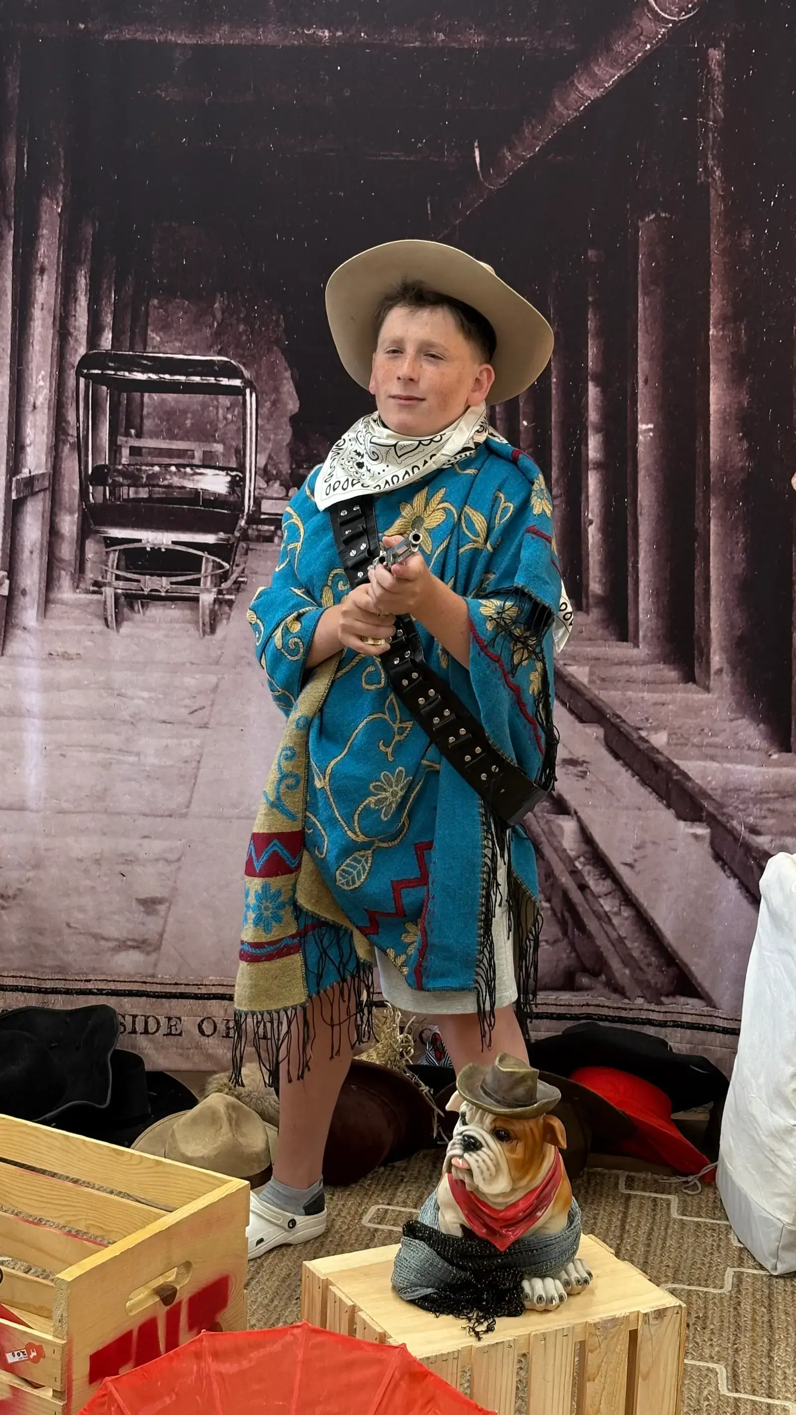 A camper in full Wild West dress-up costume posing against an old-time saloon backdrop