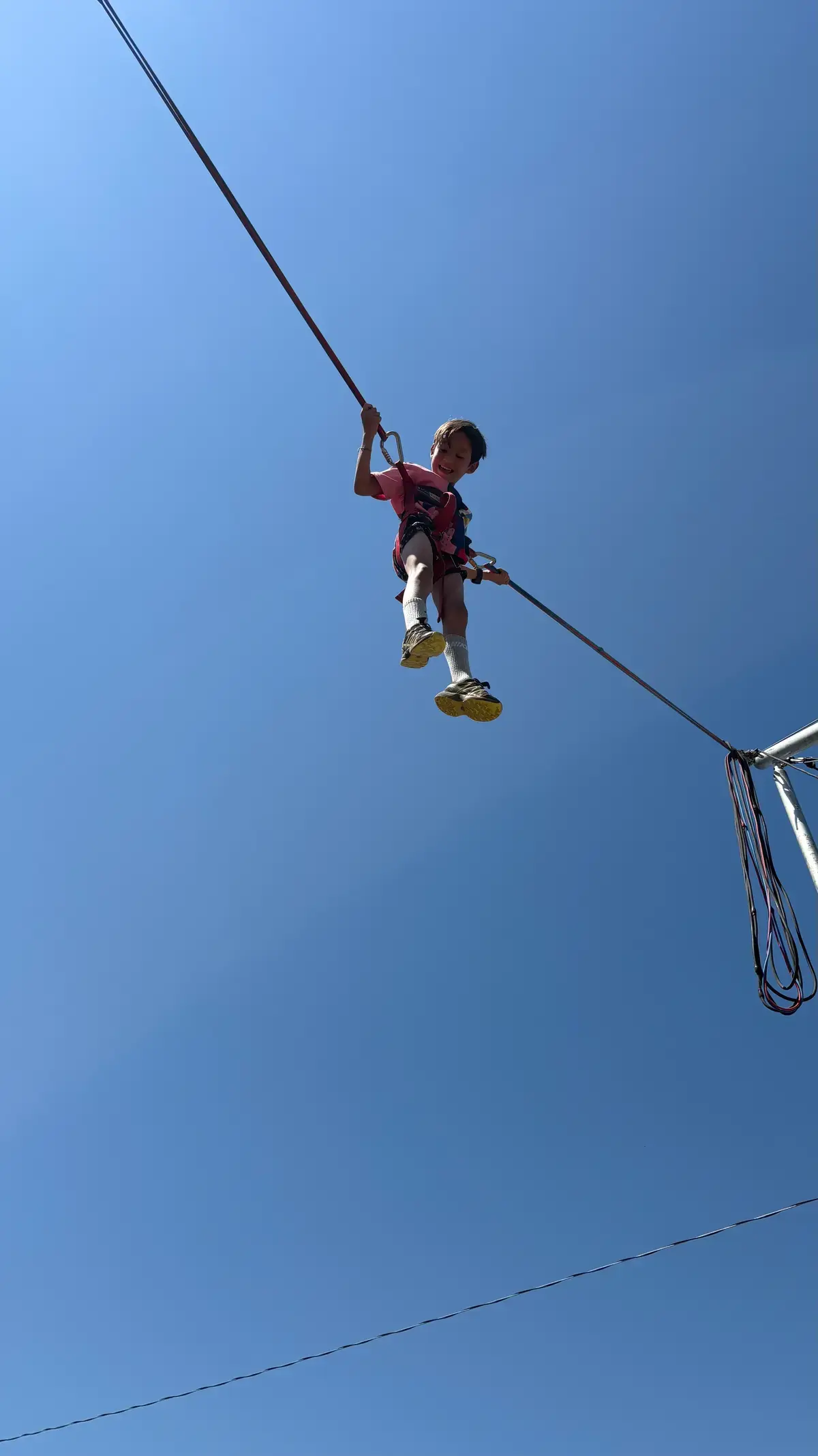 Camper mid-bounce against a blue Colorado sky on the bungee trampoline