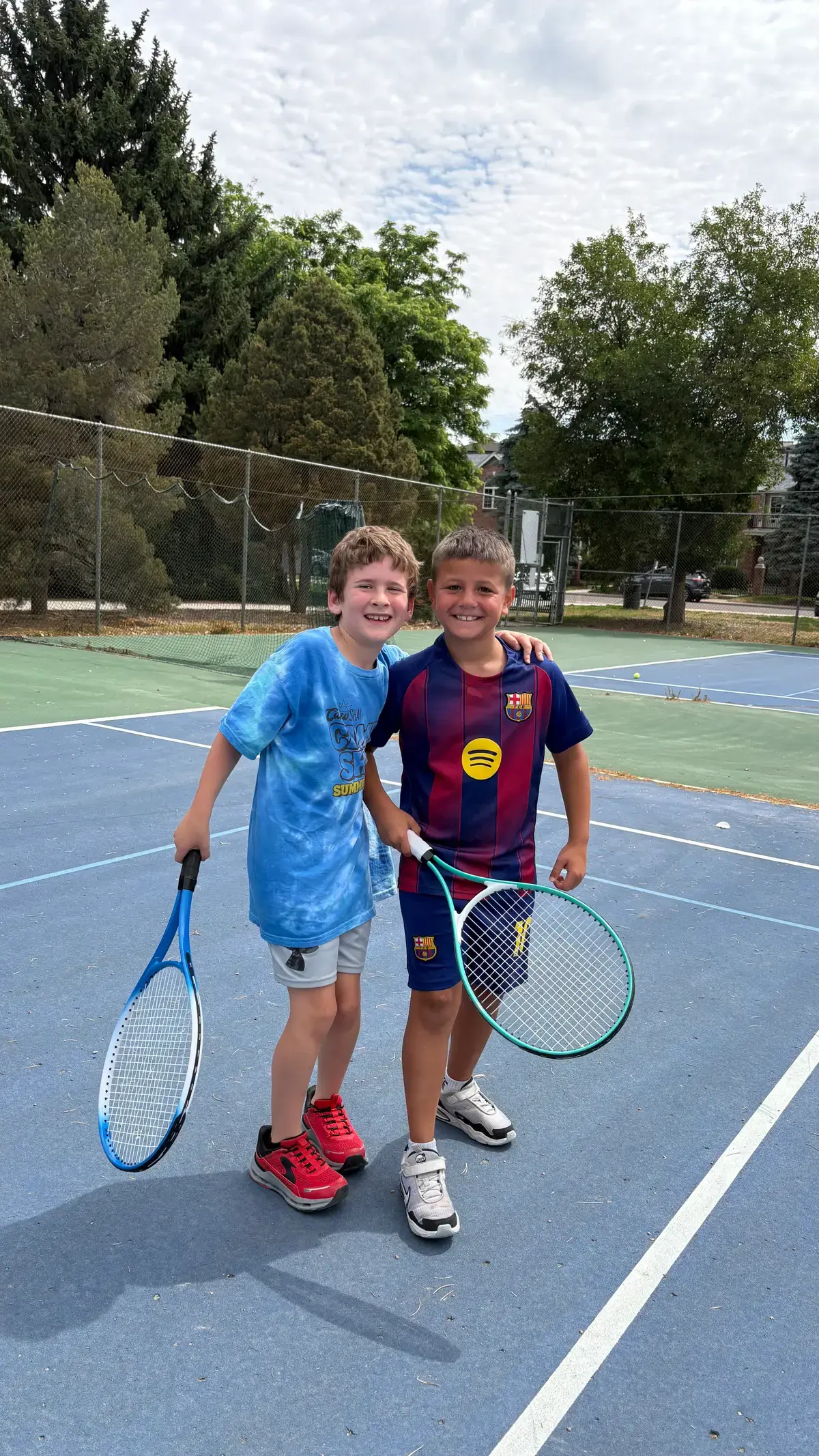 Two campers with rackets on the tennis court