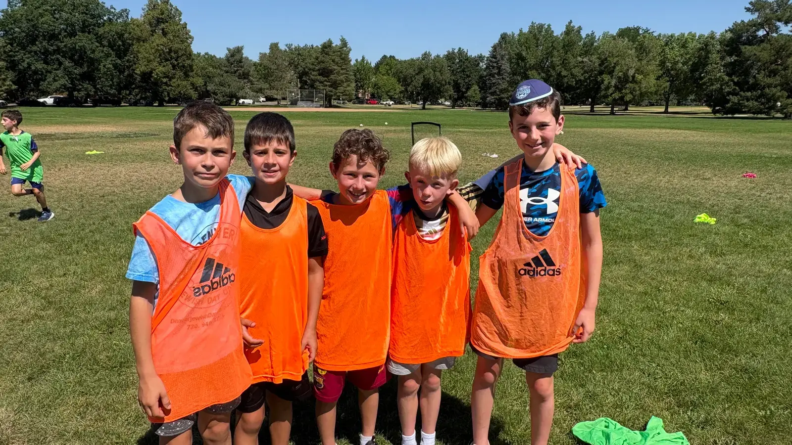 Junior campers in orange pinnies grouped together on the field