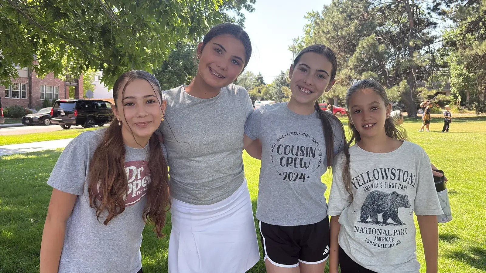 Four campers standing arm in arm on the grass, all smiling