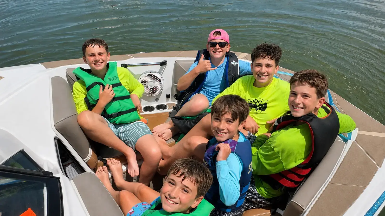 Sabra campers in life jackets laughing together on a boat out on the reservoir