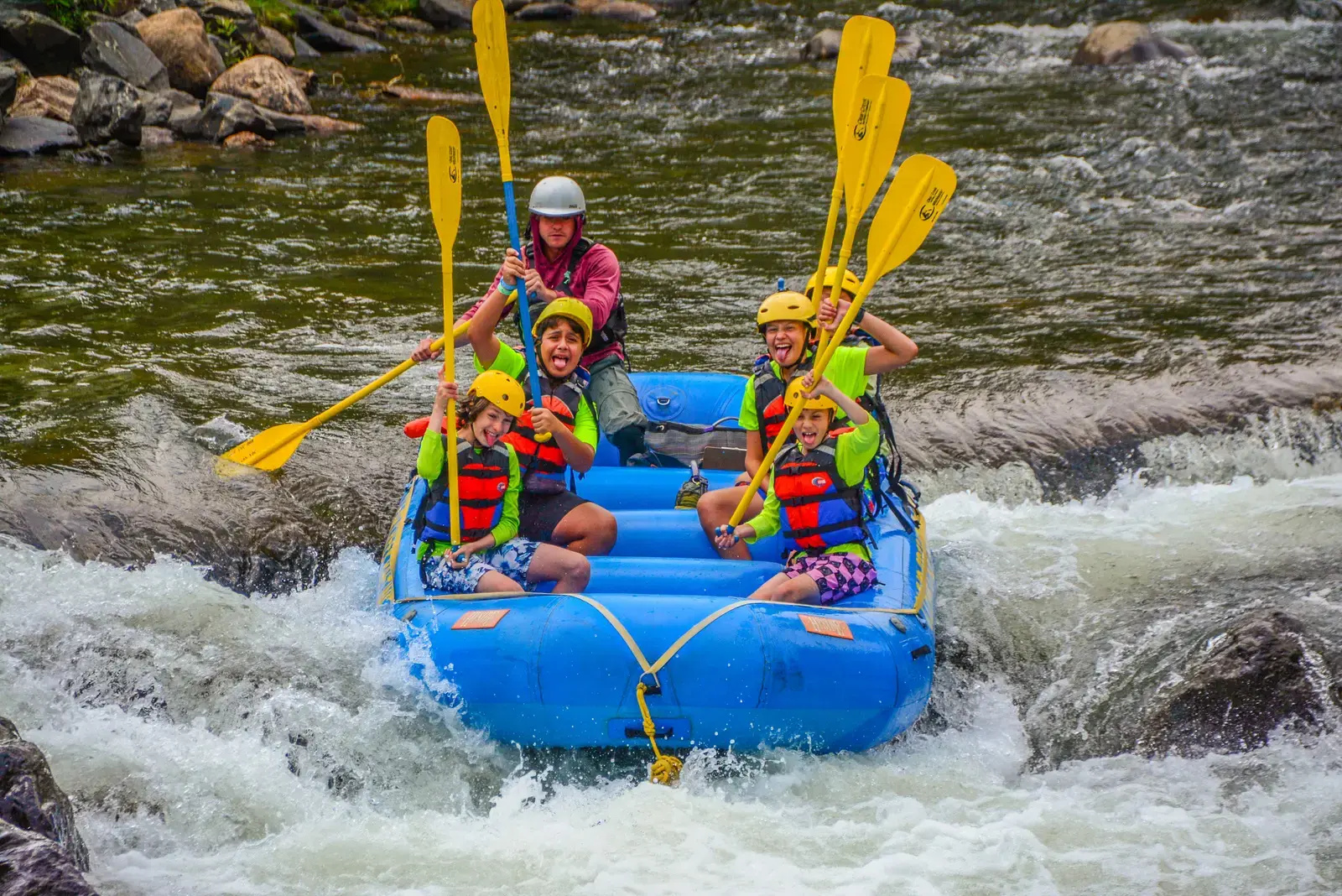 Campers paddling a raft through whitewater rapids