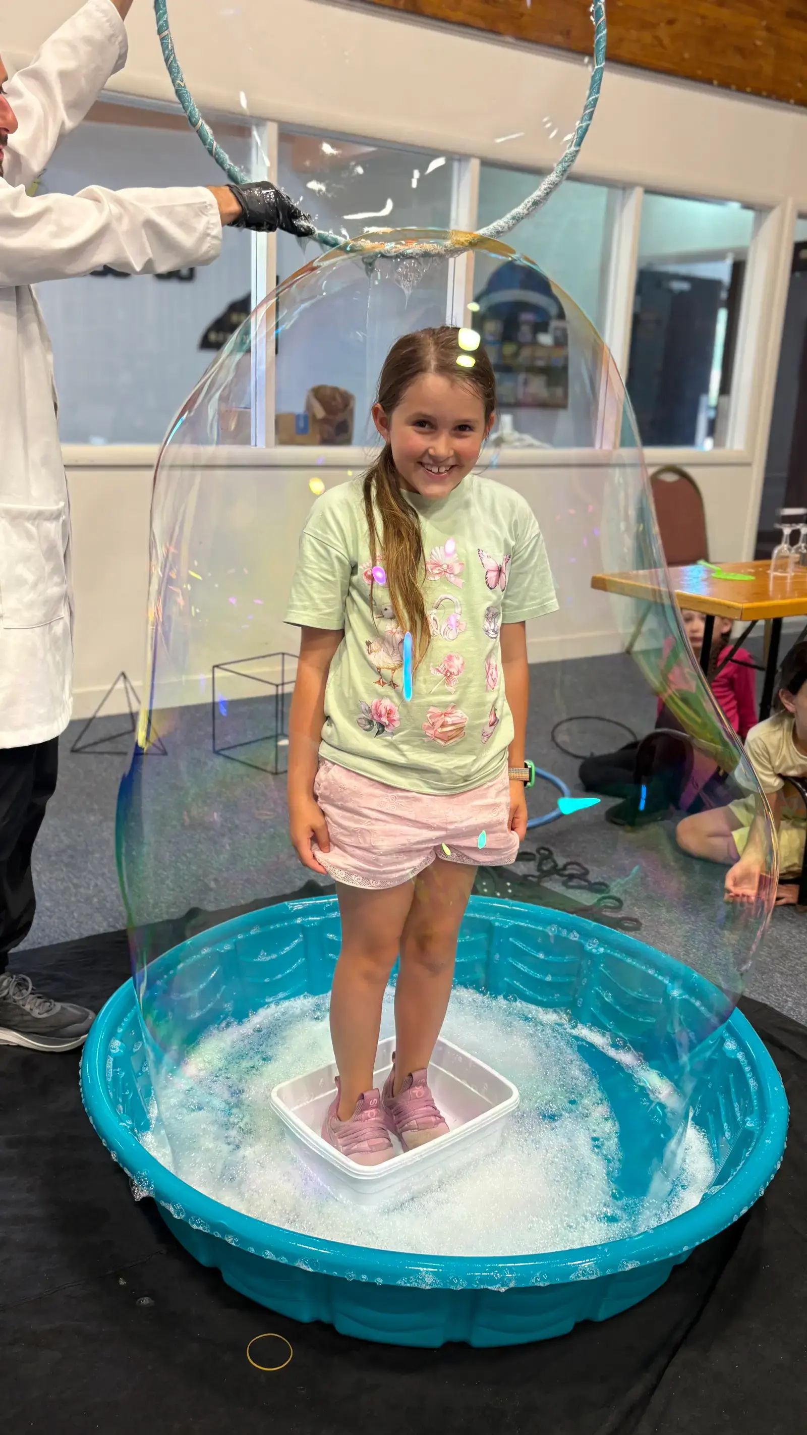 A camper standing inside a giant soap bubble during the science workshop