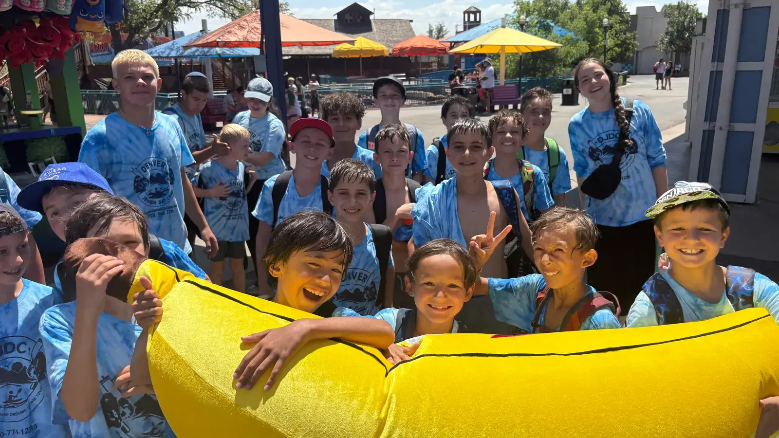 A big group of campers in tie-dye shirts crowded around a raft at the amusement park